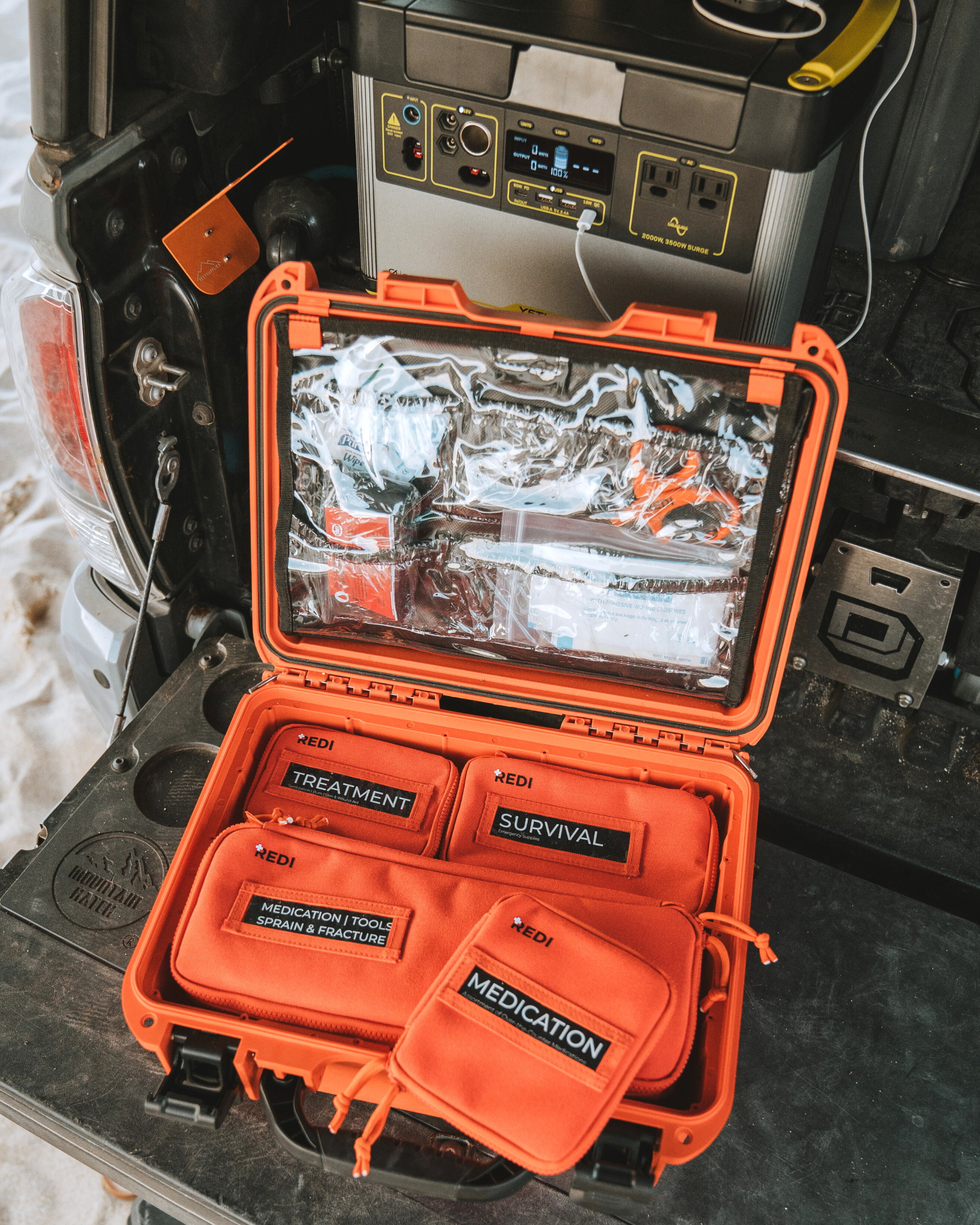 Labeled pouches inside the Roadie Pro + first aid kit as it sits on the bed of an overlanding truck.