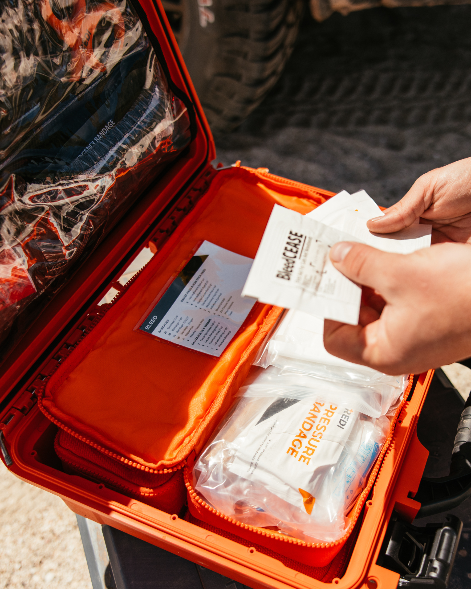 A man opening the bleed pouch of the Roadie Pro + and holding up Bleedcease, used to control bleeding. 