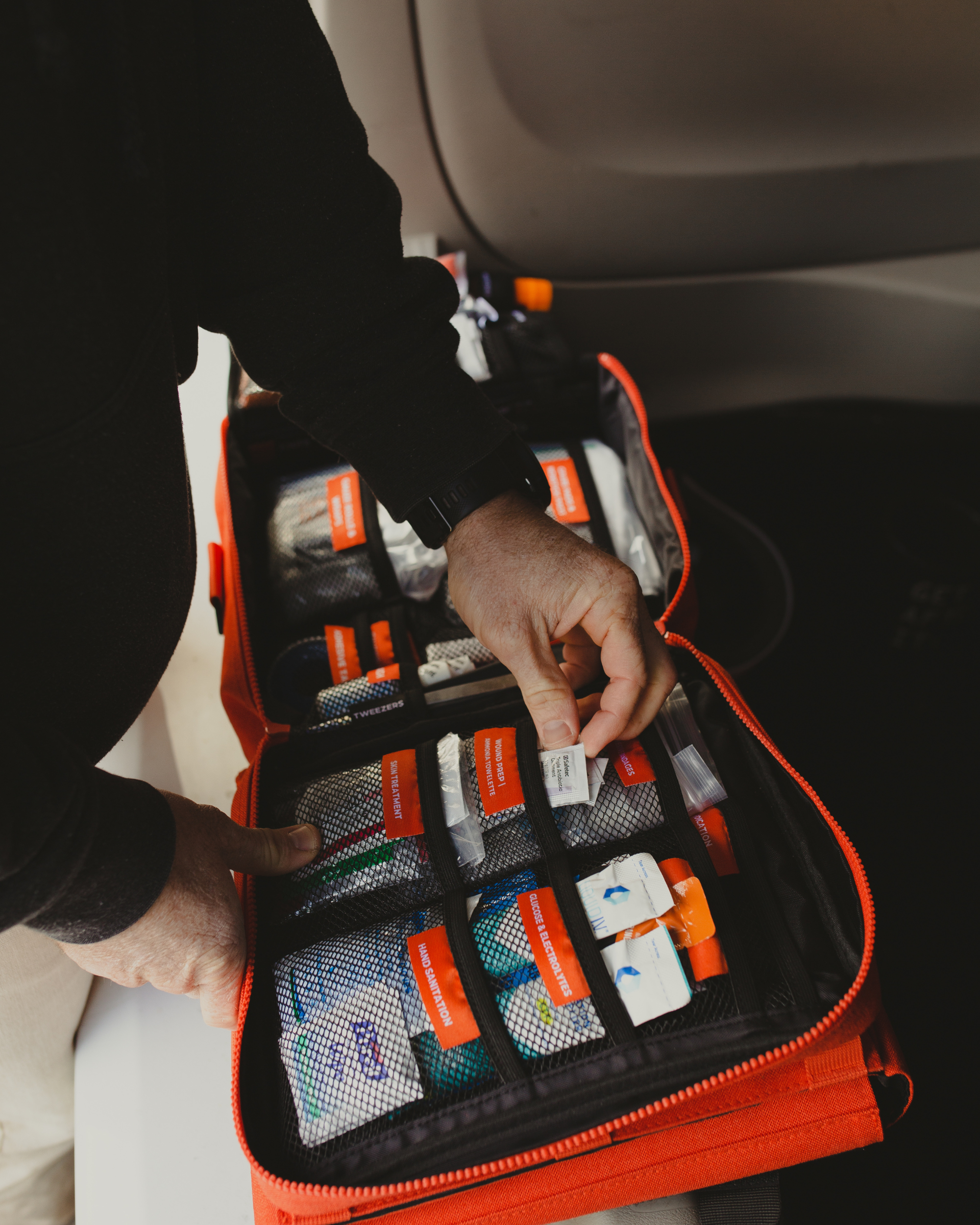 A man pulling an item out of the Wound Prep | Ammonia Towelette pocket of the Roadie Pro, car first aid kit. 