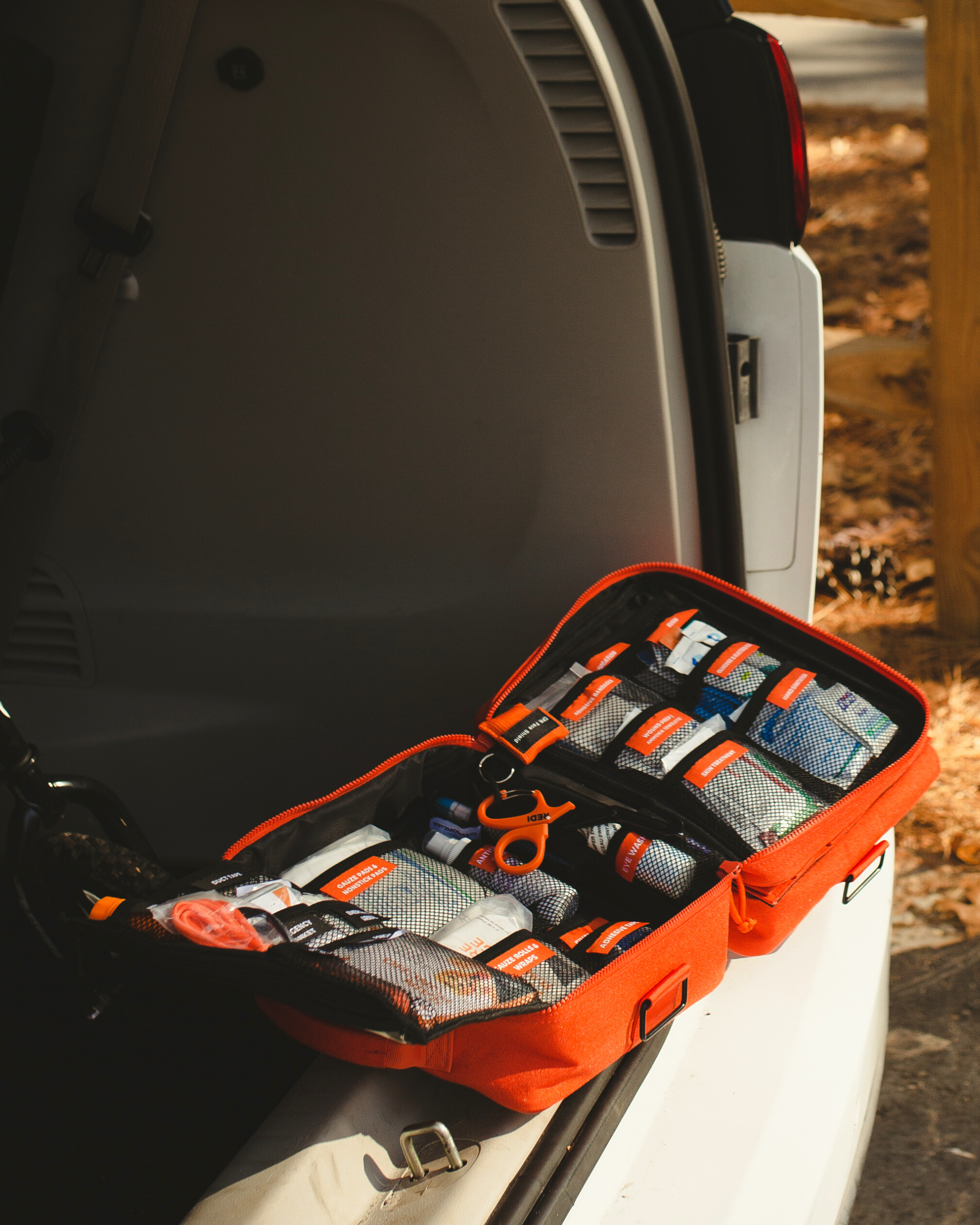 Roadie first aid kit opened up in the trunk of a car at the park. 