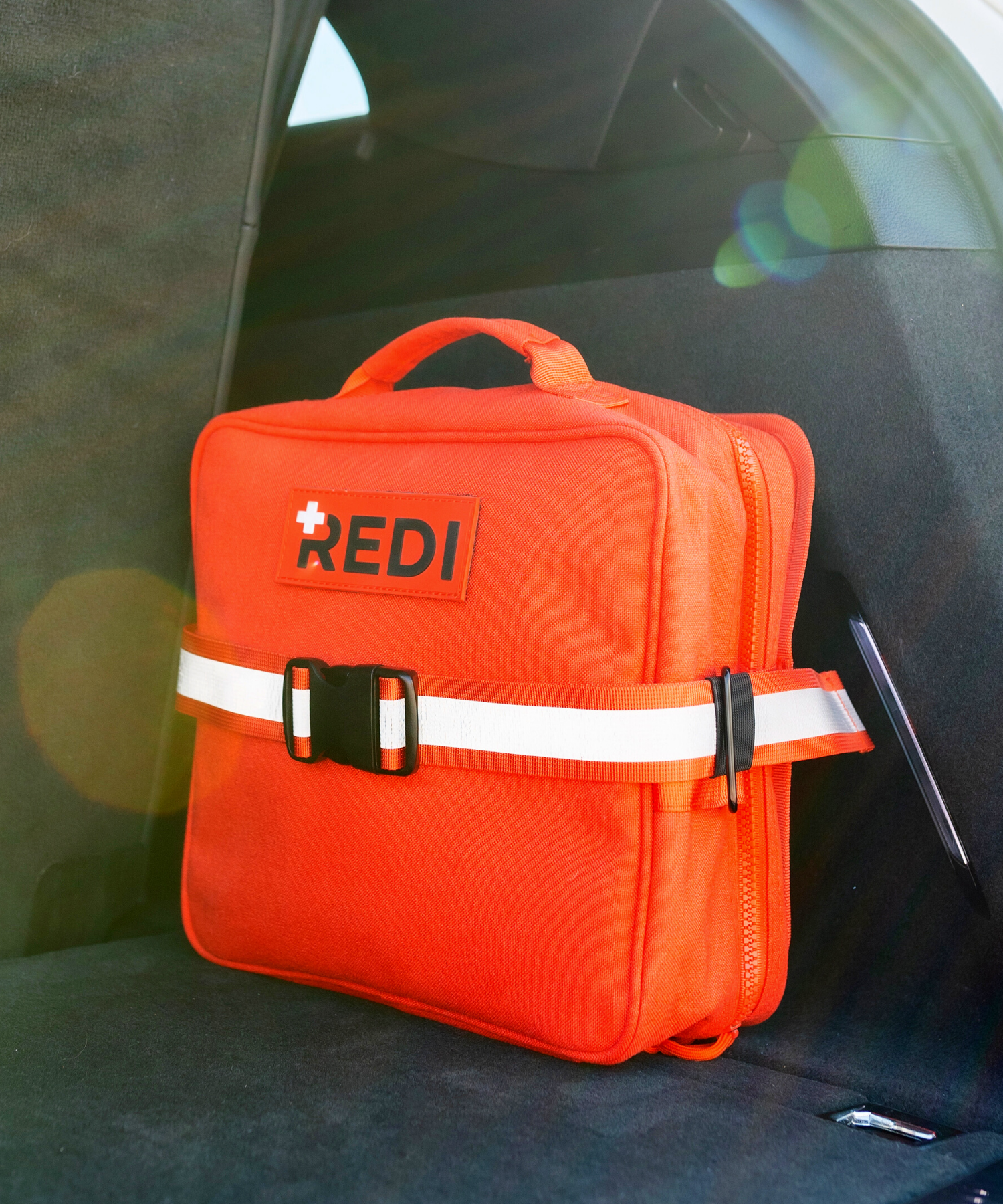 An orange Roadie car, first aid kit attached in the trunk of a car, ready for emergencies on the road.