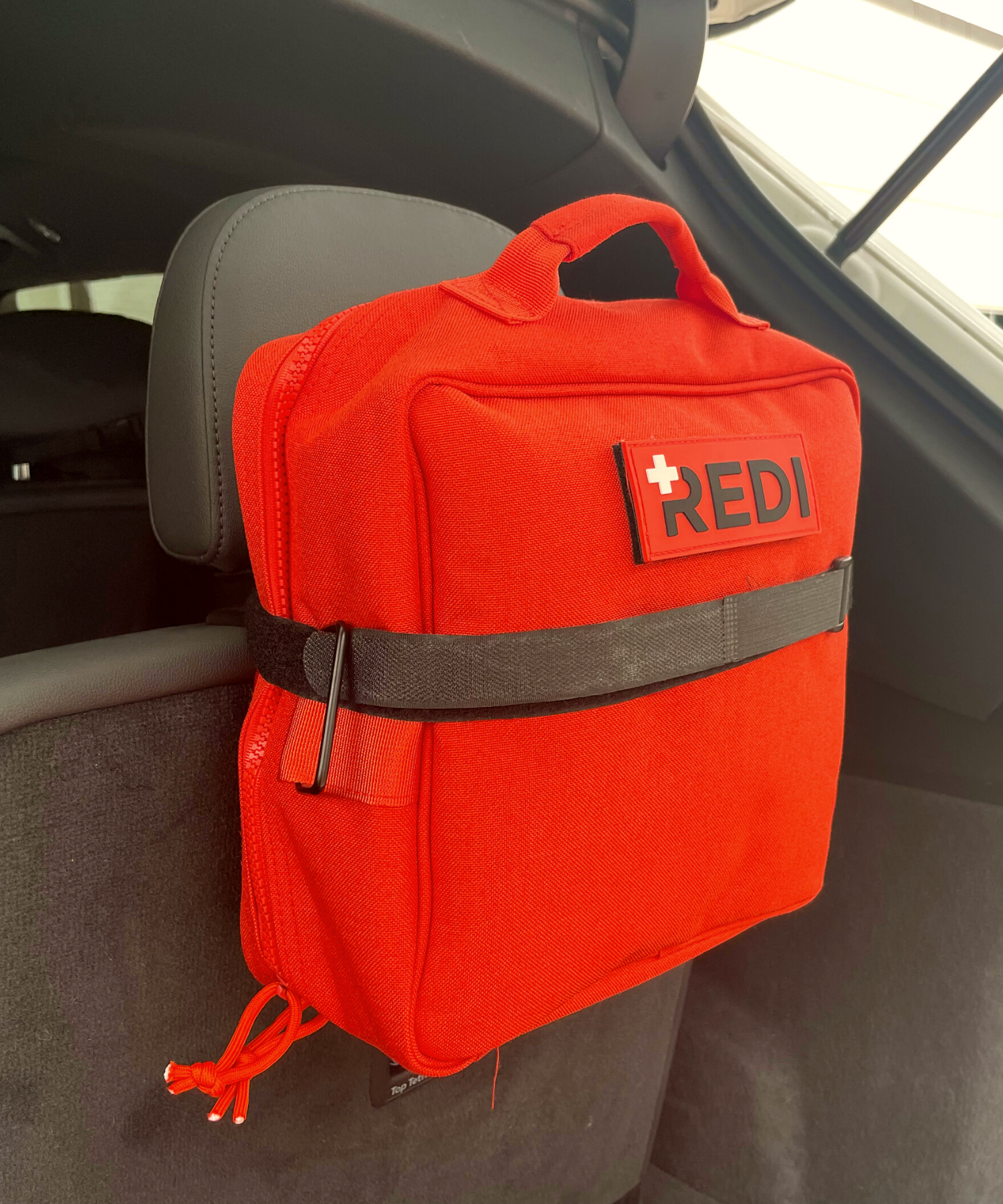 The Roadie, car first aid kit being secured to the headrest with the large velcro strap (car attachment).  