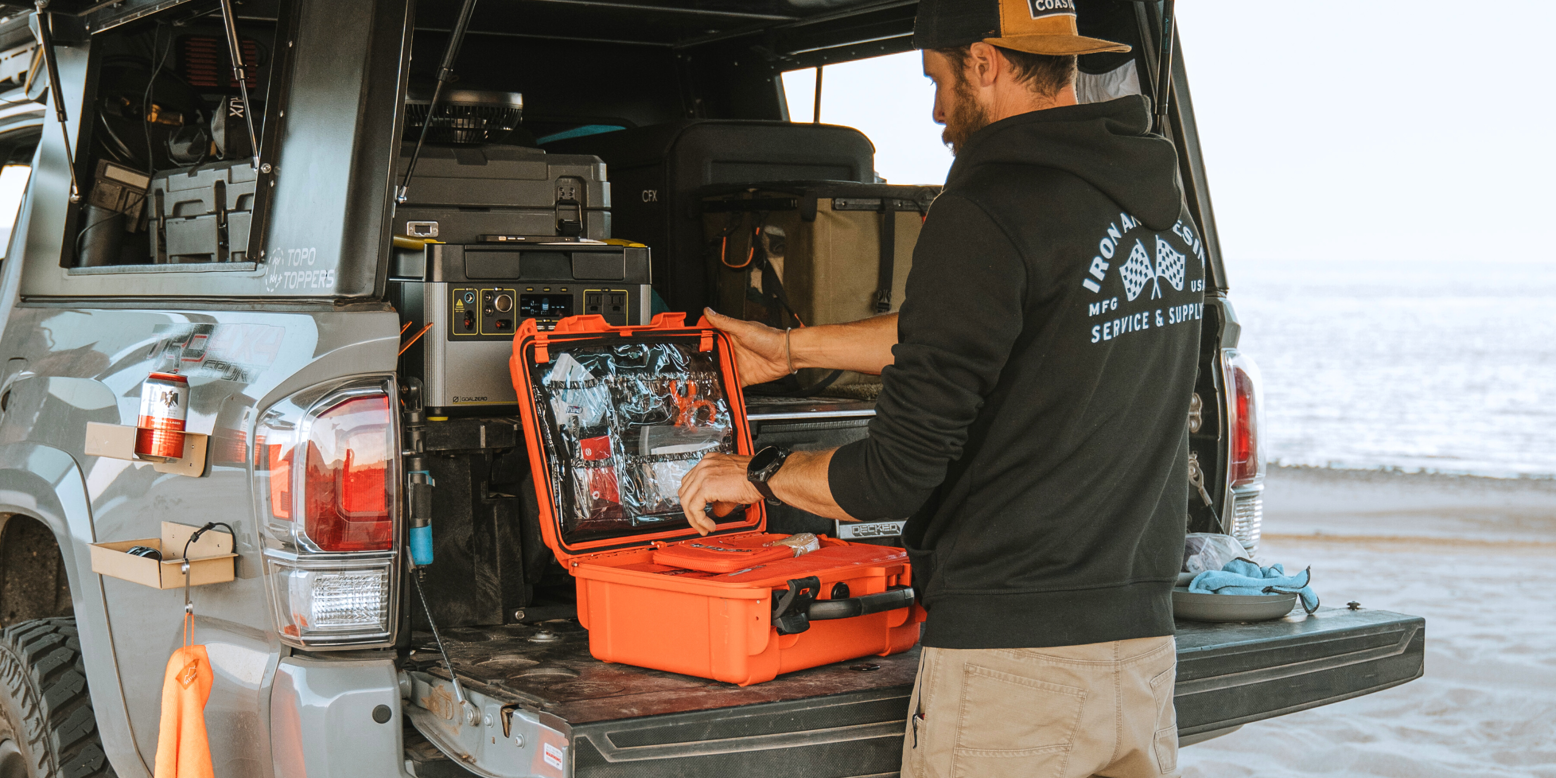 A man opening the Roadie Pro + in the back of his truck at the beach. 